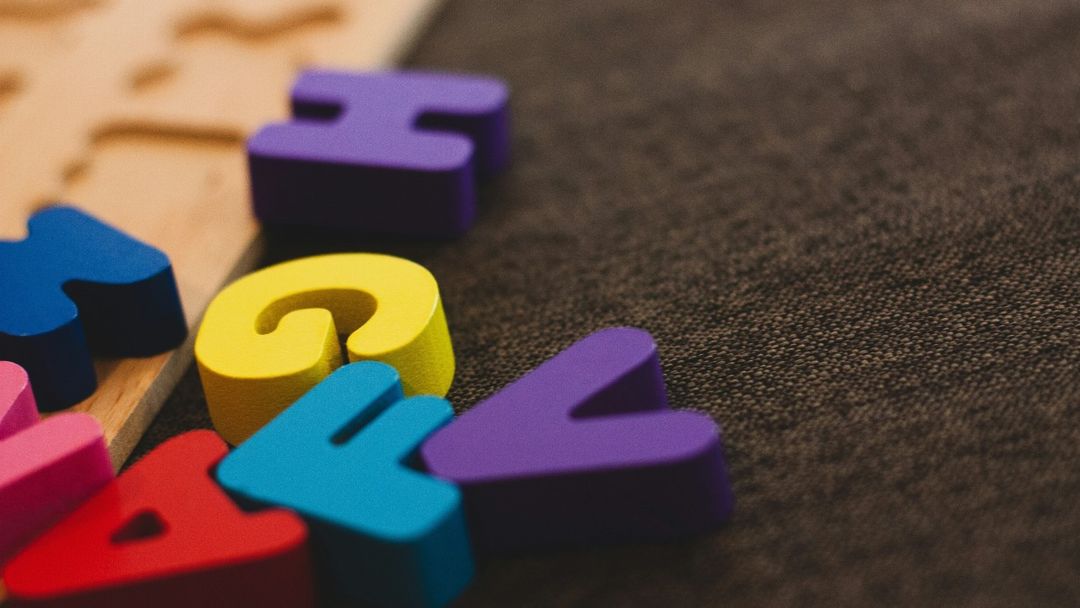 Colorful letters and a question mark scattered on a desk